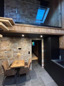 een eetkamer met een tafel en een stenen muur bij L'Oxalis villa, l'Edelweiss in Bonnelles