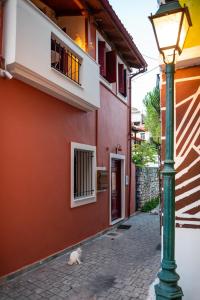 Tollmere Hospitality Λύχνος suite في ليفاديا: قطة تجلس بجوار مبنى به مصباح شارع