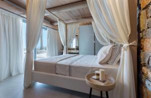 una camera da letto con un letto con tende bianche e un tavolo di Artisan's House a Sitia Altre 28 foto