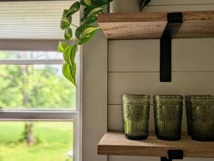 three green glasses sitting on a shelf next to a window at Redwing Farm Cottage - Mountain Views and Firepit! in Bedford