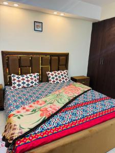 a bed with a colorful comforter and two pillows at Syed Apartment 104 in Islamabad