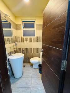 a bathroom with a tub and a toilet and a door at Syed Apartment 104 in Islamabad