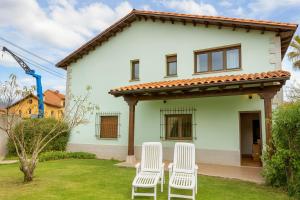 un gruppo di sedie bianche di fronte a una casa di Casa vacacional La Vicoca a Poo de Llanes