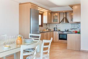 eine Küche mit einem Tisch mit Stühlen und einem Kühlschrank in der Unterkunft Avlaki Bay House in Arvanitakaíïka
