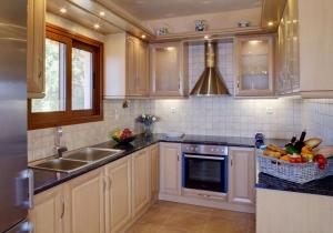 eine Küche mit weißen Schränken und einer Spüle und einem Obstkorb in der Unterkunft Avlaki Bay House in Arvanitakaíïka + 24 Fotos