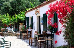 a restaurant with tables and chairs and red flowers at Kallista House in Kourtaíïka