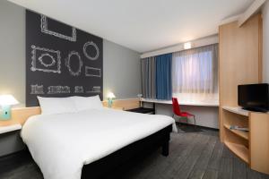 a hotel room with a white bed and a red chair at Ibis Szczecin Centrum in Szczecin