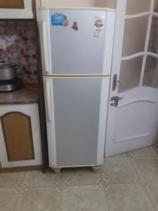 a white refrigerator in a kitchen next to a door at Harmony Homestay Couple & Family friendly prime location Easy access to Mall Rd -City view in Solan