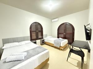 Un dormitorio con dos camas y un escritorio. en Pousada Dona Lidia Express, en Campo Mourão