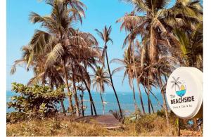 a sign in front of palm trees and the ocean at Beachside in Anjuna