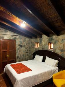 een slaapkamer met een groot bed in een stenen muur bij Los Andes - Restaurant & Bungalows in Cieneguilla