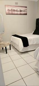 a bedroom with a bed and a chair on a tiled floor at Vaal Home near Aquadome in Vanderbijlpark +13 photos