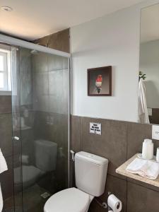 a bathroom with a toilet and a glass shower at Suites da Dani in Areal