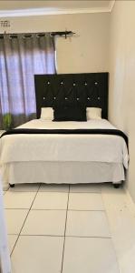 a bedroom with a large bed with a black headboard at Vaal Home near Aquadome in Vanderbijlpark