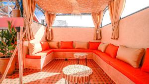 een rode bank in een kamer met ramen bij riad Orazur in Marrakesh