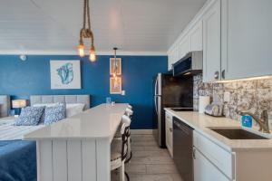 a kitchen with blue walls and a bed in a room at EPIC Gulf & Beach Views with Balcony, Beach Supplies, & Pool in St. Pete Beach