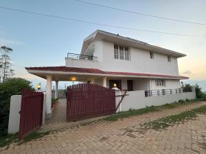 a white house with a red fence in front of it at Sathya Holidays Evermist Stay in Ooty
