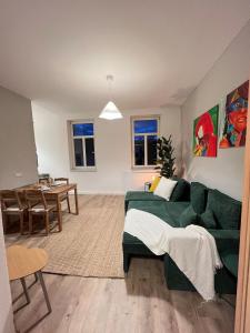 a living room with a green couch and a dining room at Liebe Wohnung Pension in Penig