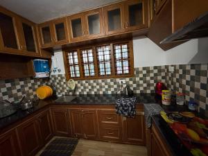 a kitchen with wooden cabinets and black and white tiles at Sathya Holidays Evermist Stay in Ooty