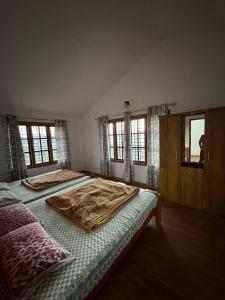 two beds in a bedroom with windows at Sathya Holidays Evermist Stay in Ooty