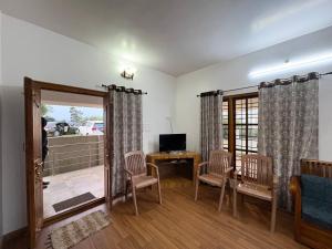 a living room with a table and chairs and a television at Sathya Holidays Evermist Stay in Ooty