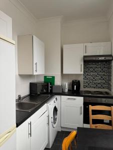 een keuken met witte kasten en een wasmachine bij Smart Junction in Norwood