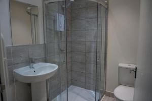 een badkamer met een douche, een wastafel en een toilet bij Town Centre Apartments in Dewsbury
