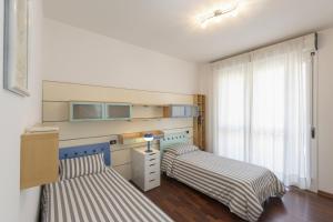 ein Schlafzimmer mit zwei Betten und einem Schreibtisch und einem Fenster in der Unterkunft La Piazzetta in San Giovanni in Persiceto