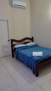 a bedroom with a bed with a blue blanket and a door at Casa florida suite- seguridad y ubicación ideal in Ciudad Guayana