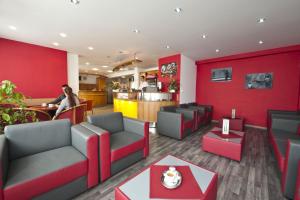 a restaurant with red walls and couches and a counter at Hotel Plus in Bratislava