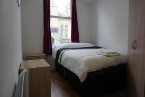 a small bedroom with a bed with a window at Town Centre Apartments in Dewsbury
