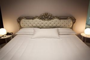 a bedroom with a bed with a headboard and two lamps at Hotel Villa Nabila in Reggiolo