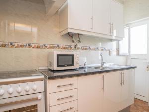 a white kitchen with a microwave and a sink at Akivillas Lagos Zircon in Lagos +16 photos