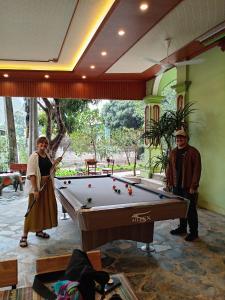 a man and a woman standing next to a pool table at Sun Mountain Hostel in Nguyên Ngoại