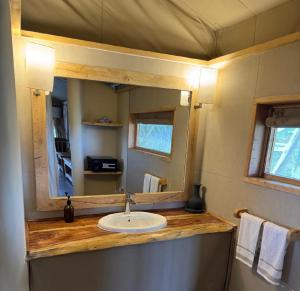 a bathroom with a sink and a mirror at Oloiba Nkuti Lodge in Masai Mara