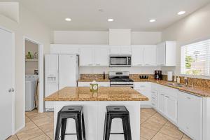 パーム・スプリングスにあるVista-Verdeの白いキャビネット付きのキッチン、カウンター(スツール付)