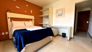 a bedroom with a bed with a blue blanket at Oasis do Mar Hotel - A melhor vista de Itapema in Itapema