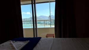 a bedroom with a bed and a large window at Oasis do Mar Hotel - A melhor vista de Itapema in Itapema