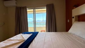 a bedroom with a bed and a large window at Oasis do Mar Hotel - A melhor vista de Itapema in Itapema