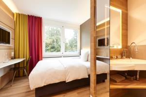 Una habitación de hotel con una cama, un lavabo y una ventana. en Steinenschanze Charming City & Garden Hotel, en Basilea