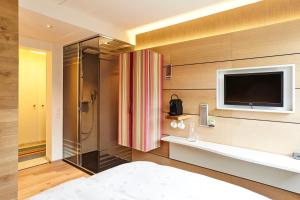 a bedroom with a shower and a television on a wall at Steinenschanze Stadthotel in Basel