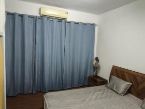 a bedroom with blue curtains and a bed at Studio chambre salon cuisine in Dakar