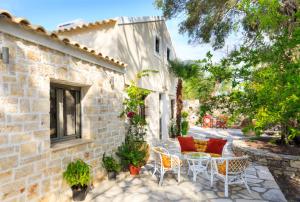 Olive Cottage في Petrátika: فناء فيه كراسي وطاولات ومبنى