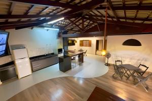 a kitchen and living room with a table and chairs at Cobertura Jacuzzi e Area Gourmet Sao Judas in Divinópolis