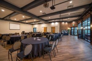 Coast Nisku Inn & Conference Centre في نيسكو: قاعة حفلات بها طاولات وكراسي وشاشة +117 صورة