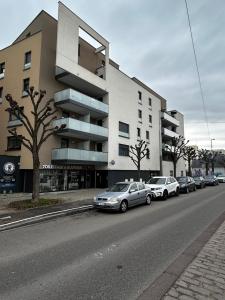 una fila de autos estacionados frente a un edificio en Apparemment 3 pièce Strasbourg Ilkirch graffenstaden, en Illkirch-Graffenstaden