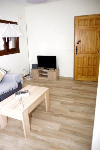 Refugio tranquilo cerca de las piscinas في كانديليدا: غرفة معيشة مع طاولة قهوة وتلفزيون