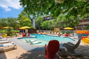 a swimming pool with chairs and a playground at Aiden Austin City Hotel in Austin