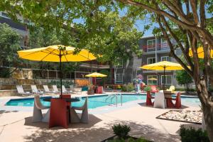 a pool with tables and chairs and umbrellas at Aiden Austin City Hotel in Austin