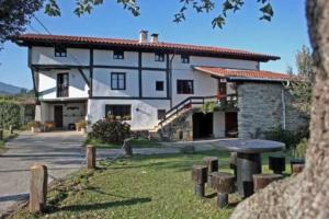 a large white house with a table in front of it at Albergue Rural Montebaserria in Ziortza-Bolibar
